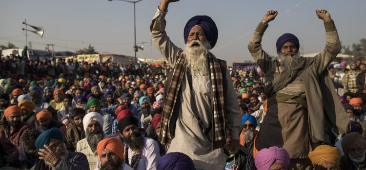 DELHI, INDIA - DECEMBER 18: Farmers shout slogans as they participate in a protest at the Delhi Singhu border on December 18, 2020 in Delhi, India. Hundreds of thousands of farmers from surrounding states have been protesting on the outskirts of Delhi for weeks, blockading highways leading to the capital. Farmers say they are protesting against laws that deregulate the sale of crops, which they say will put them at risk of losing their livelihoods and land to big corporations. The government has said that the reforms are necessary to improve the efficiency of the agricultural sector, which is heavily dependent on government subsidies to survive. (Photo by Anindito Mukherjee/Getty Images)